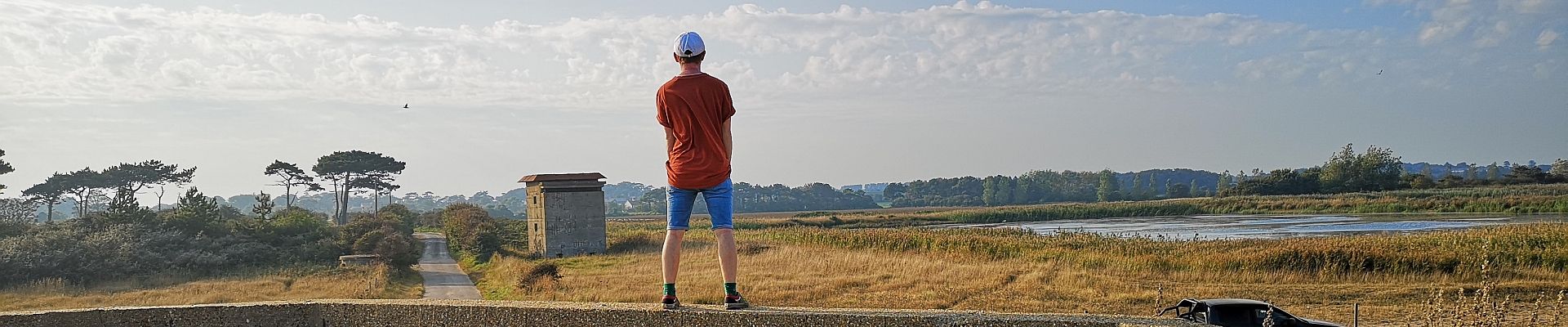 Young man looks inland at lake and Bawdsey landscape Suffolk